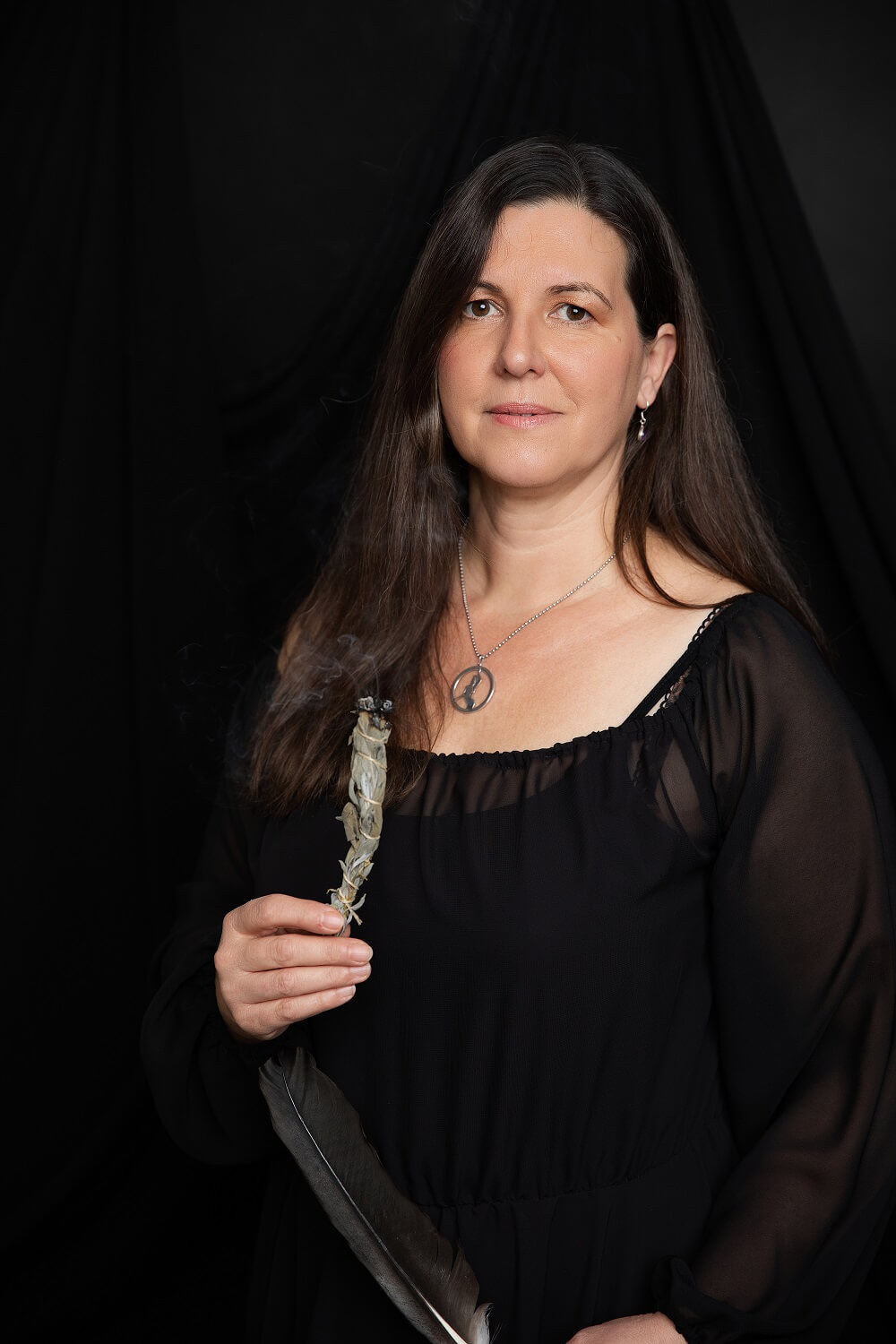 Portrait von Kirsten Landauer, Räucherwerk und Feder in den Händen haltend